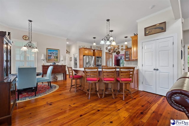 kitchen featuring an inviting chandelier, stainless steel appliances, a kitchen bar, and dark wood-type flooring