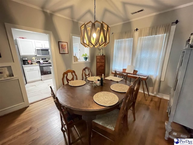 dining room with ornamental molding, light hardwood / wood-style floors, and a notable chandelier