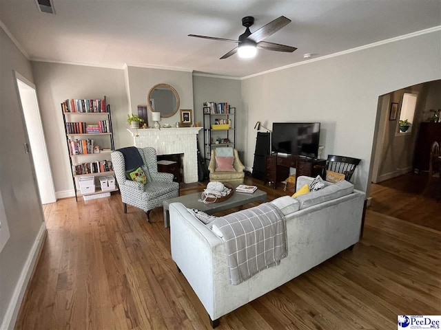 living room with ornamental molding, hardwood / wood-style floors, ceiling fan, and a fireplace