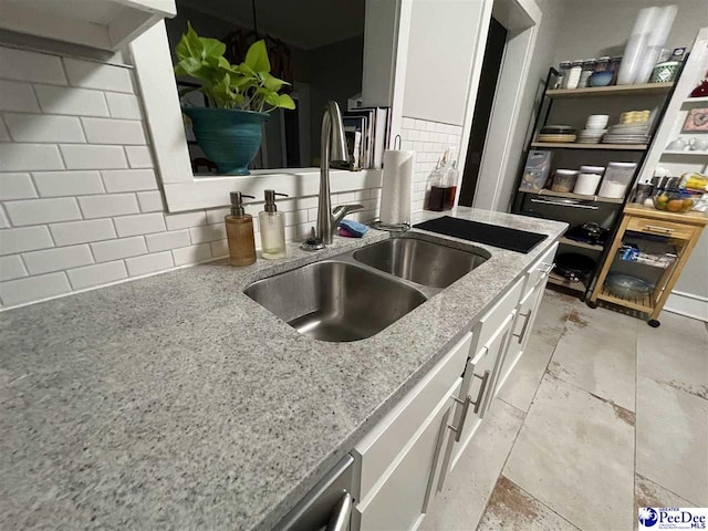 kitchen featuring backsplash, light stone countertops, sink, and white cabinets