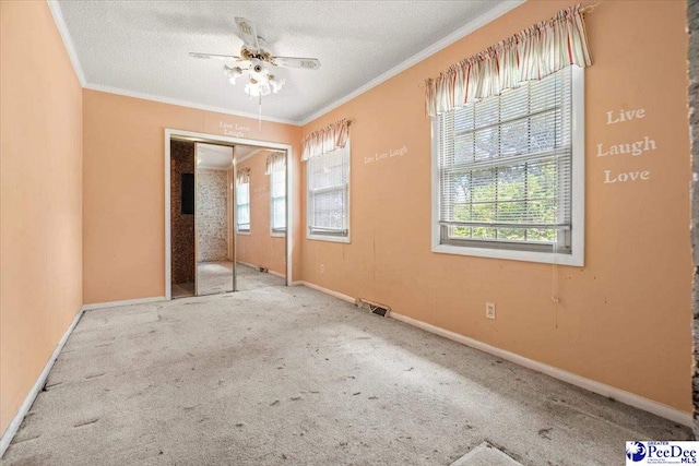 unfurnished bedroom featuring ornamental molding, carpet floors, multiple windows, and a textured ceiling