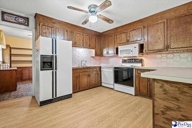 kitchen featuring sink, white appliances, ceiling fan, backsplash, and light wood-type flooring