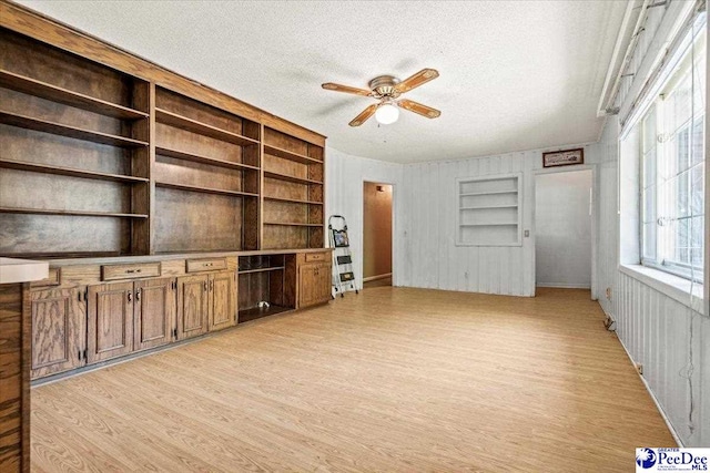 unfurnished living room with ceiling fan, light hardwood / wood-style floors, a textured ceiling, and built in features