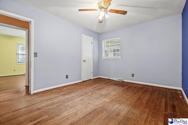 empty room with hardwood / wood-style flooring, ceiling fan, and a textured ceiling