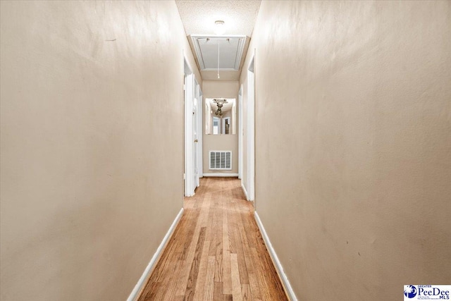 hall featuring light hardwood / wood-style flooring and a textured ceiling