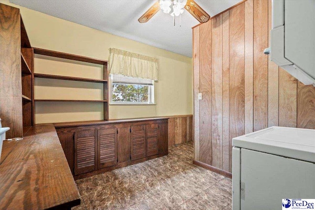 interior space featuring washer / clothes dryer, a textured ceiling, wooden walls, and ceiling fan