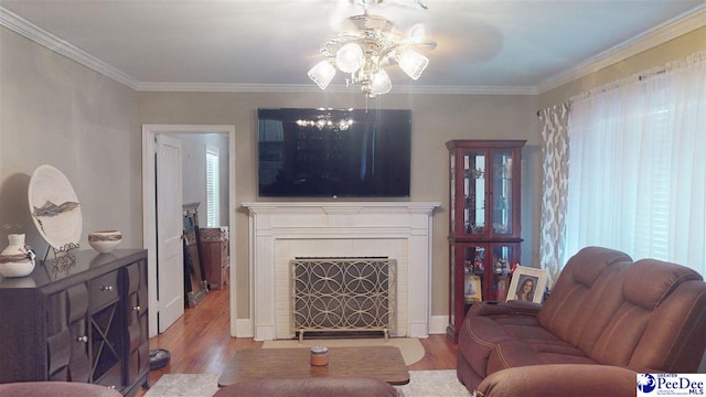 living room with a tiled fireplace, wood-type flooring, and ornamental molding