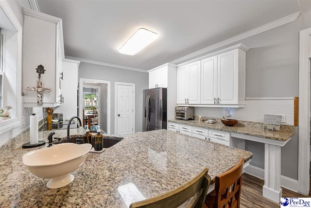 2409 Sarazen Ct, Florence, SC 29506 - kitchen featuring freestanding refrigerator, white cabinets, light stone countertops, ornamental molding, and dark wood-style floors