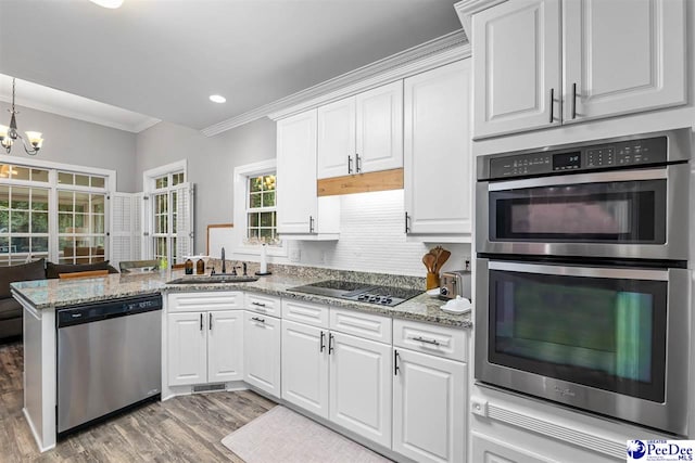 2409 Sarazen Ct, Florence, SC 29506 - kitchen with appliances with stainless steel finishes, a sink, crown molding, light wood-type flooring, and white cabinets