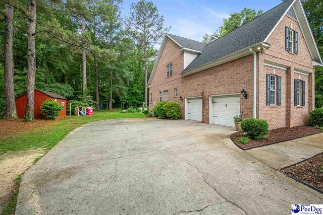 2409 Sarazen Ct, Florence, SC 29506 - view of side of property with a shingled roof, brick siding, a garage, driveway, and a lawn