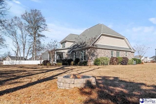 rear view of property featuring a yard and a fire pit