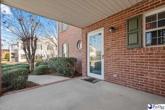 doorway to property with a patio area and brick siding