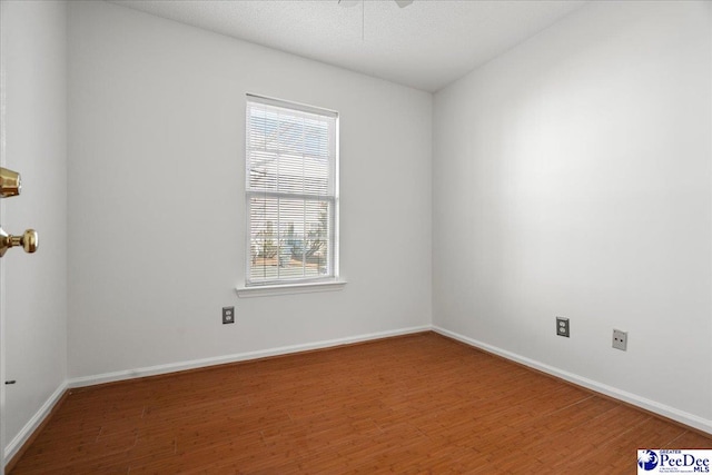 spare room featuring ceiling fan, a textured ceiling, baseboards, and wood finished floors