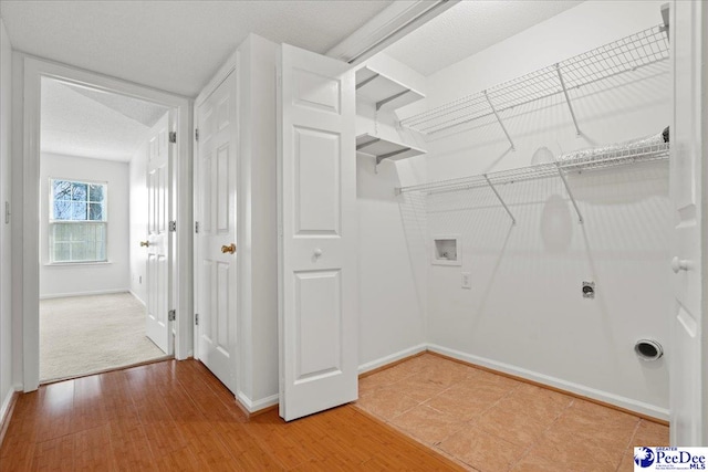 washroom featuring hookup for a washing machine, laundry area, baseboards, and wood finished floors