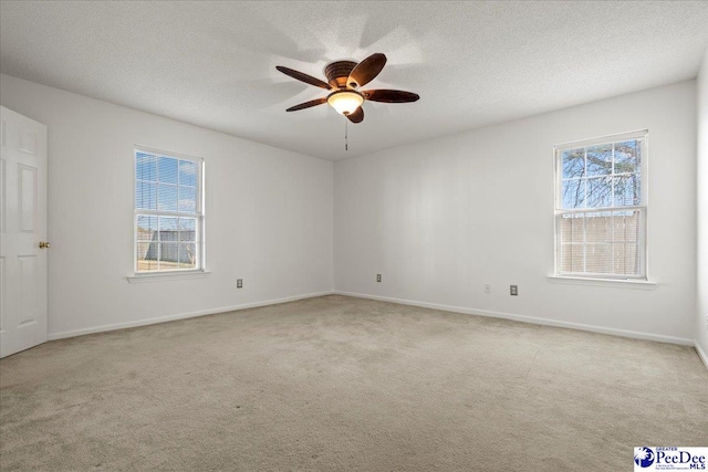 unfurnished room with a ceiling fan, light colored carpet, and a textured ceiling