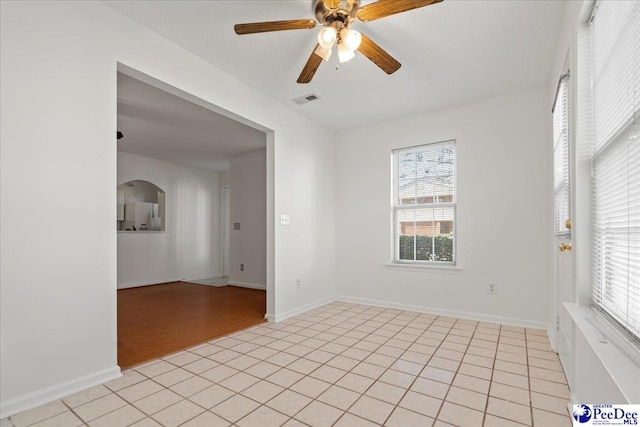 unfurnished room featuring a ceiling fan, visible vents, baseboards, and light tile patterned flooring