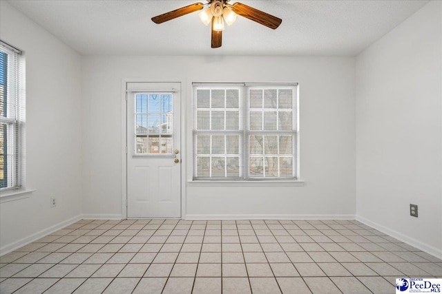 spare room with a ceiling fan, a textured ceiling, and baseboards