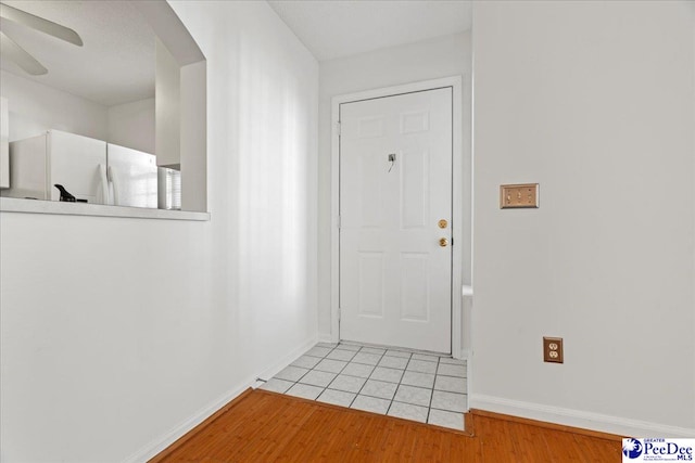 foyer entrance featuring light wood-style floors, baseboards, and a ceiling fan