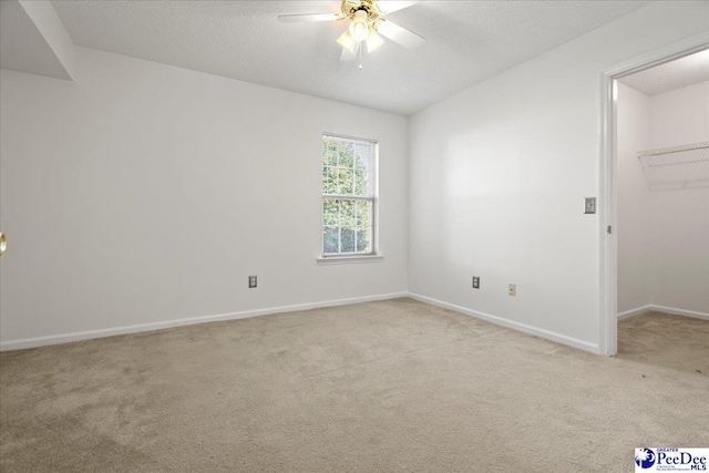 empty room with light carpet, a textured ceiling, and baseboards