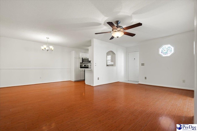 unfurnished living room with ceiling fan with notable chandelier, a textured ceiling, wood finished floors, and baseboards