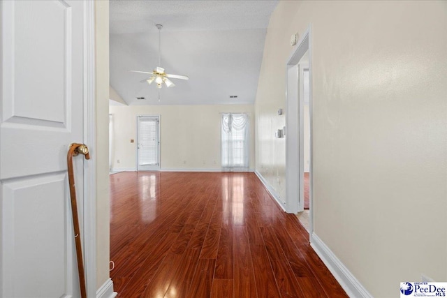 unfurnished living room with lofted ceiling, ceiling fan, wood finished floors, and baseboards