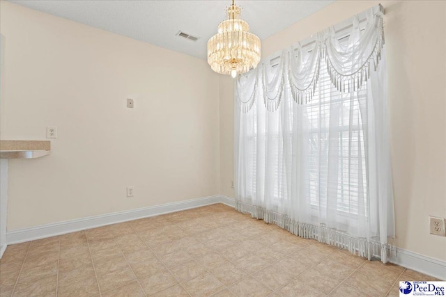 unfurnished dining area featuring visible vents, baseboards, and an inviting chandelier