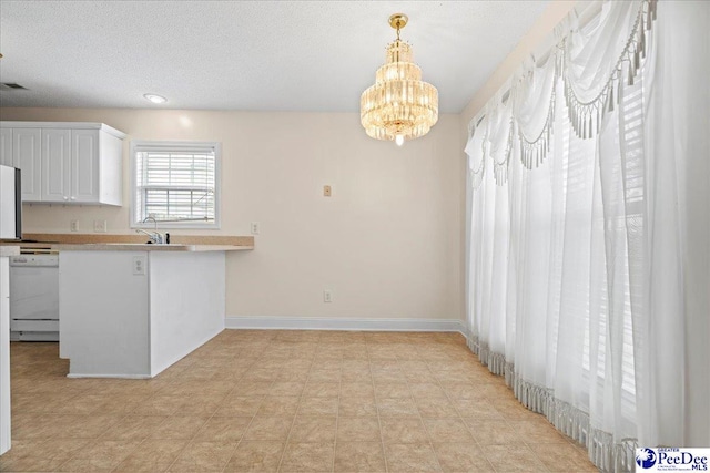 kitchen with baseboards, white cabinets, light countertops, dishwasher, and pendant lighting