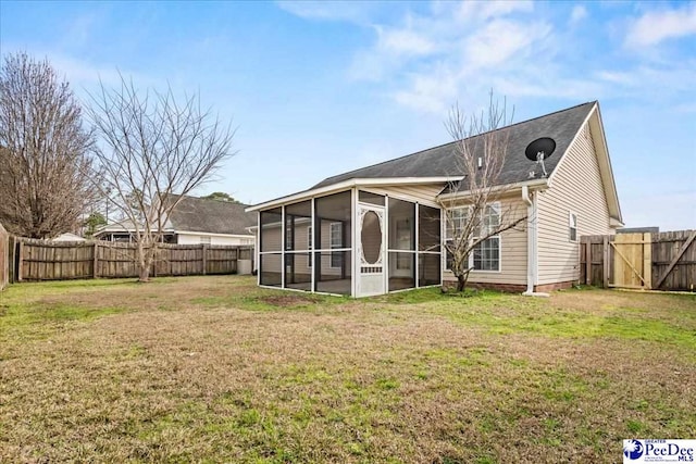 rear view of house featuring a sunroom, a fenced backyard, a lawn, and a gate