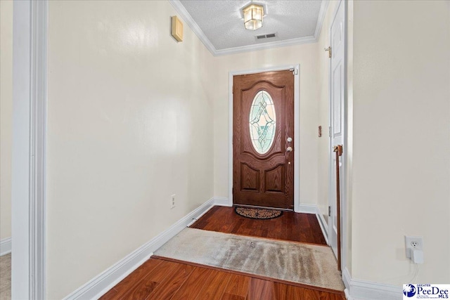 doorway featuring a textured ceiling, wood finished floors, visible vents, baseboards, and crown molding