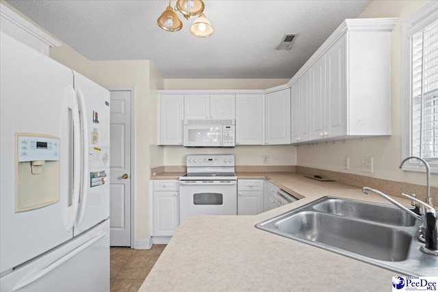 kitchen with white appliances, light countertops, visible vents, and white cabinetry