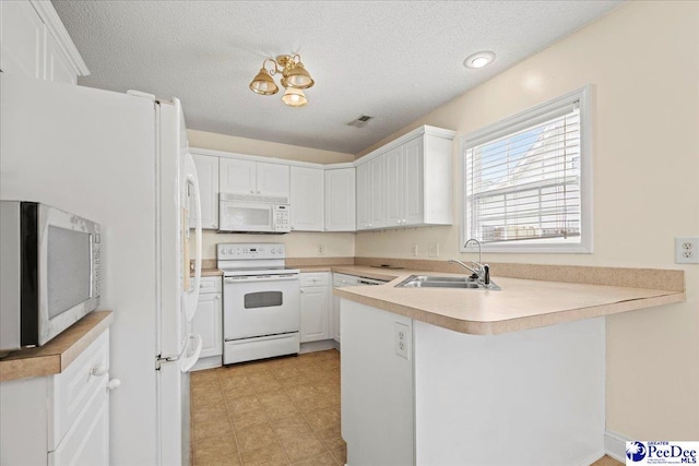 kitchen with a peninsula, white appliances, a sink, white cabinetry, and light countertops