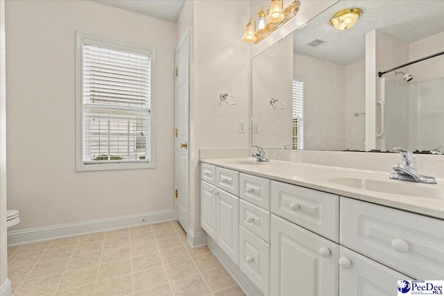 full bath with baseboards, double vanity, a sink, and a healthy amount of sunlight