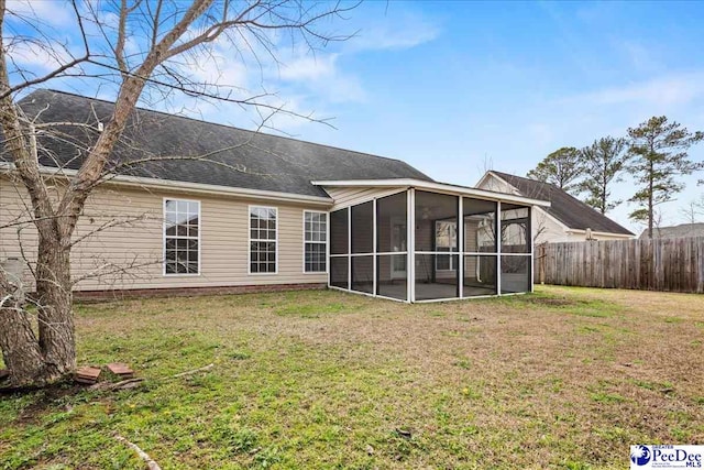 rear view of house with a yard, fence, and a sunroom