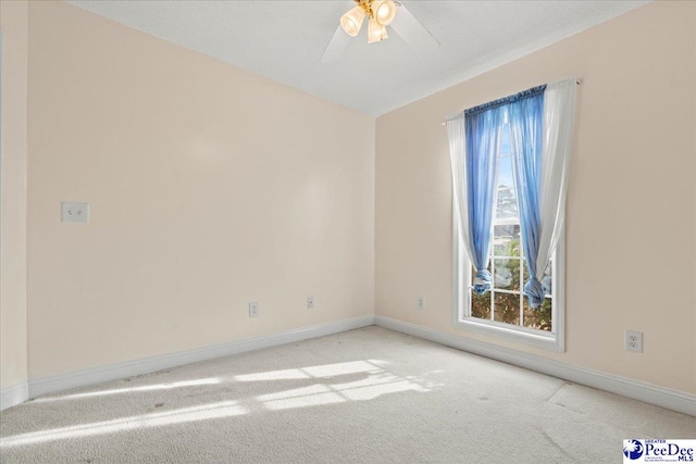 carpeted spare room with plenty of natural light, baseboards, and ceiling fan