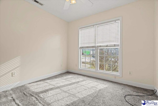 carpeted empty room with a ceiling fan, visible vents, and baseboards