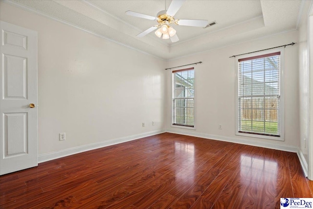 spare room featuring visible vents, crown molding, a tray ceiling, and wood finished floors