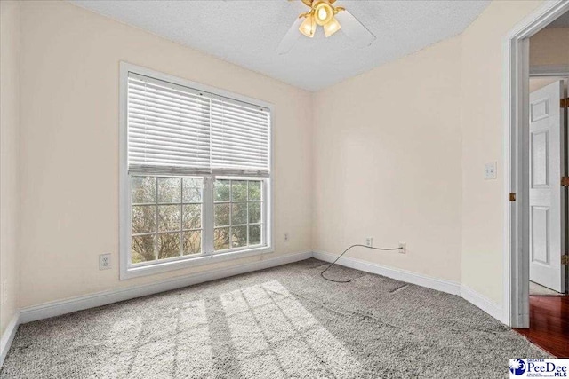 carpeted spare room featuring ceiling fan, baseboards, and a textured ceiling