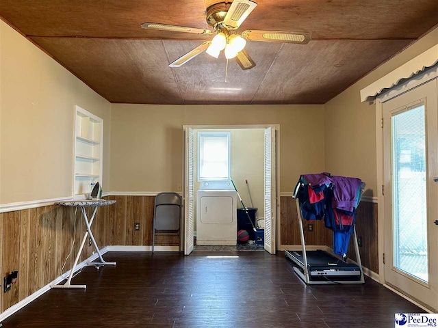 interior space featuring ceiling fan, dark hardwood / wood-style floors, built in shelves, washer / dryer, and wood walls