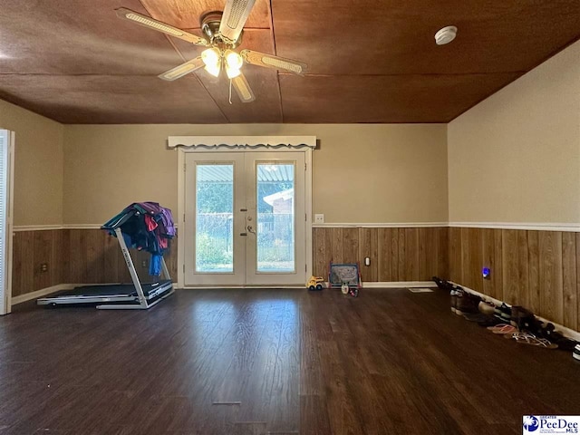 workout room featuring french doors, ceiling fan, wooden walls, and hardwood / wood-style flooring