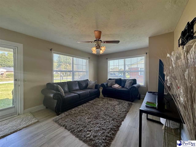 living room with ceiling fan, hardwood / wood-style flooring, and a textured ceiling