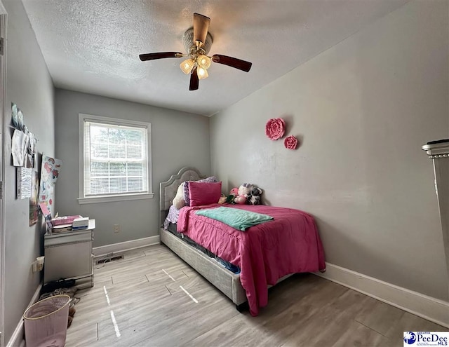 bedroom with ceiling fan, light hardwood / wood-style floors, and a textured ceiling