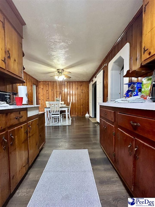 kitchen with wooden walls, ceiling fan, dark hardwood / wood-style floors, and a textured ceiling