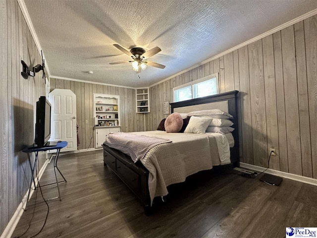 bedroom featuring crown molding, dark wood-type flooring, wooden walls, and a textured ceiling