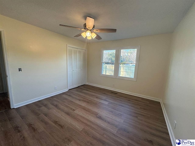 unfurnished bedroom featuring ceiling fan, dark wood-type flooring, a closet, and a textured ceiling