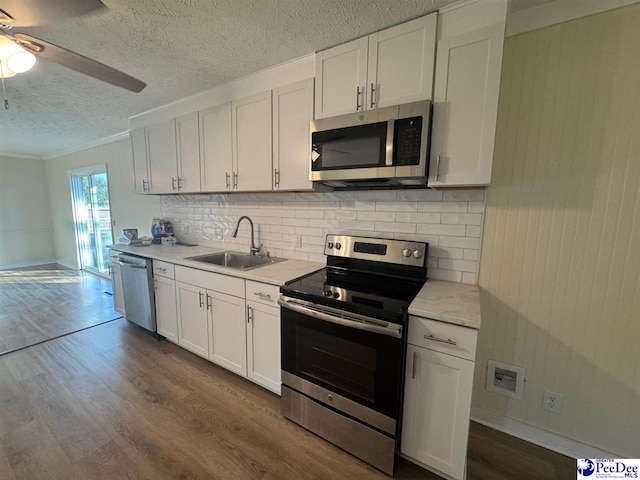 kitchen featuring appliances with stainless steel finishes, wood-type flooring, sink, white cabinets, and decorative backsplash