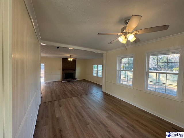 unfurnished living room with crown molding, a fireplace, dark hardwood / wood-style floors, and a textured ceiling