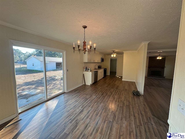 unfurnished living room featuring sink, dark hardwood / wood-style floors, ornamental molding, a textured ceiling, and ceiling fan with notable chandelier