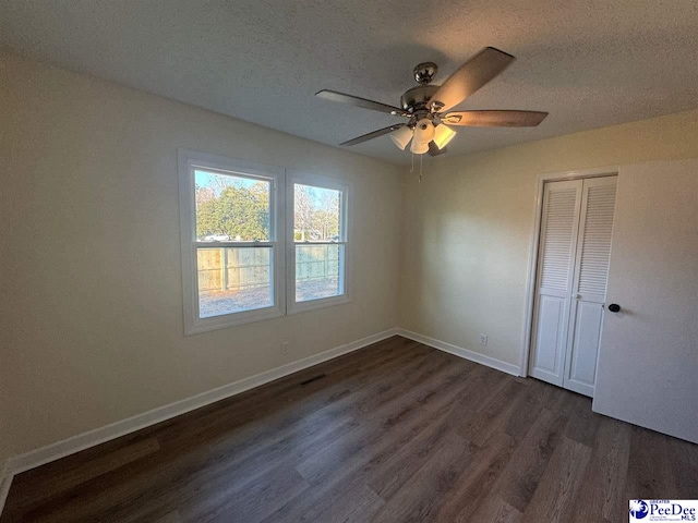 empty room with dark hardwood / wood-style flooring, ceiling fan, and a textured ceiling