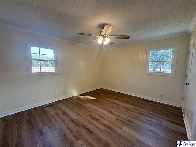 unfurnished room featuring a textured ceiling, dark wood-type flooring, ornamental molding, and a healthy amount of sunlight