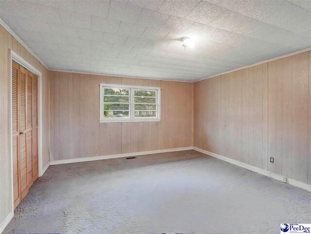 1709 N Irby St, Florence, SC 29501 - unfurnished bedroom with carpet, baseboards, wooden walls, a closet, and crown molding